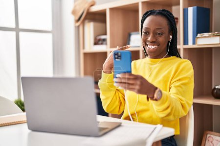Téléchargez les photos : Belle femme noire faisant appel vidéo avec smartphone souriant heureux pointant avec la main et le doigt - en image libre de droit