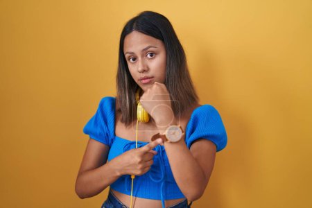 Téléchargez les photos : Jeune femme hispanique debout sur fond jaune pressé pointant vers regarder le temps, l'impatience, regardant la caméra avec une expression détendue - en image libre de droit