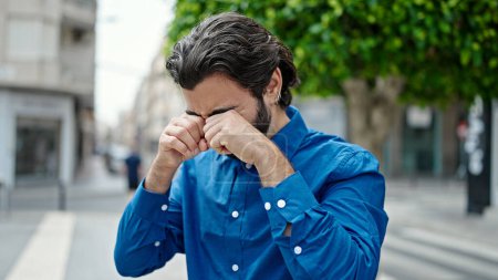 Photo for Young hispanic man rubbing the eyes at street - Royalty Free Image