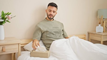 Photo for Young hispanic man sitting on bed being sick at bedroom - Royalty Free Image