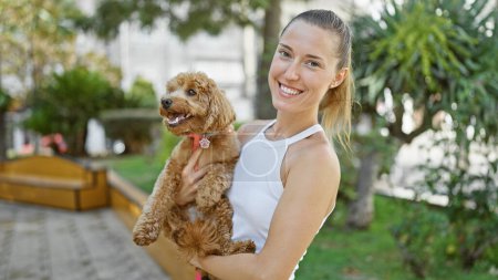 Téléchargez les photos : Jeune femme caucasienne avec chien souriant étreignant au parc - en image libre de droit