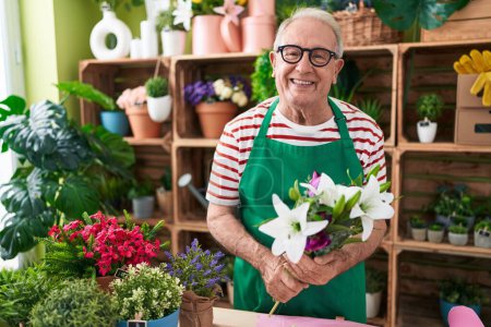 Téléchargez les photos : Homme moyen aux cheveux gris fleuriste tenant un bouquet de fleurs à la boutique de fleurs - en image libre de droit