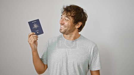Foto de Joven seguro y feliz sostiene alegremente su pasaporte australiano, sonriendo sobre un fondo blanco aislado, listo para su próxima aventura navideña - Imagen libre de derechos