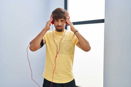 Photo for Arab man with beard wearing sportswear and headphones depressed and worry for distress, crying angry and afraid. sad expression. - Royalty Free Image