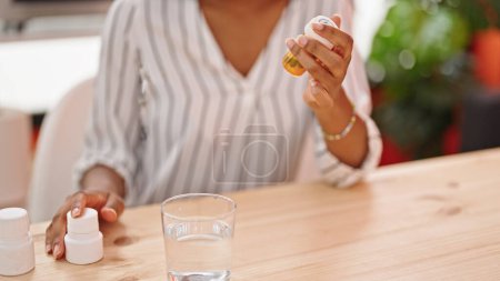 Foto de Mujer afroamericana sosteniendo pastillas botellas en el comedor - Imagen libre de derechos