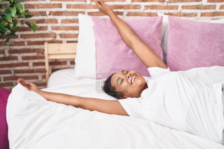 Foto de African american woman smiling confident lying on bed at bedroom - Imagen libre de derechos