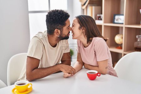 Téléchargez les photos : Homme et femme couple assis sur la table baisers à la maison - en image libre de droit