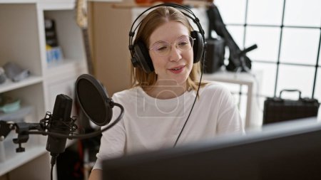Foto de Joven mujer rubia reportera de radio hablando en un programa en el estudio de radio - Imagen libre de derechos