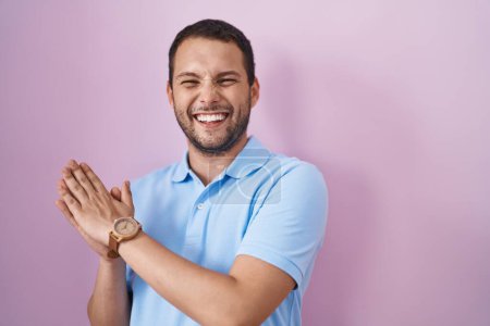 Téléchargez les photos : Homme hispanique debout sur fond rose applaudissements et applaudissements heureux et joyeux, souriant mains fières ensemble - en image libre de droit