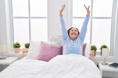 Photo for Senior woman waking up stretching arms at bedroom - Royalty Free Image