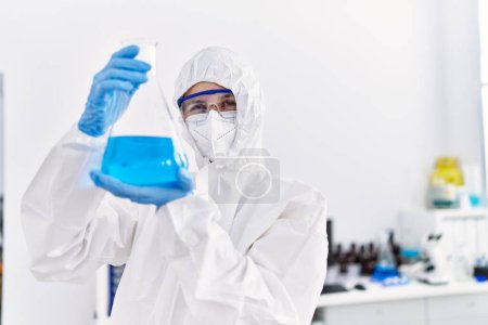 Téléchargez les photos : Jeune scientifique blonde portant un uniforme de sécurité tenant un tube à essai au laboratoire - en image libre de droit