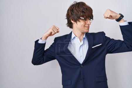 Téléchargez les photos : Jeune homme d'affaires hispanique portant des lunettes montrant les muscles des bras souriant fier. concept de fitness. - en image libre de droit