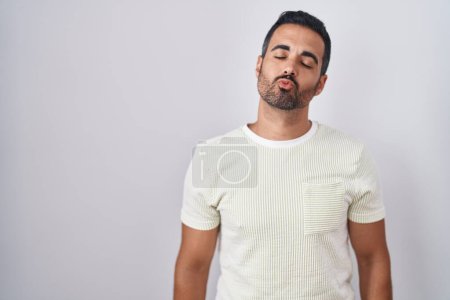 Photo for Hispanic man with beard standing over isolated background looking at the camera blowing a kiss on air being lovely and sexy. love expression. - Royalty Free Image