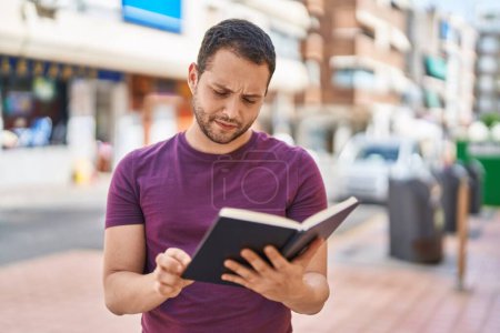 Téléchargez les photos : Young man reading book at street - en image libre de droit