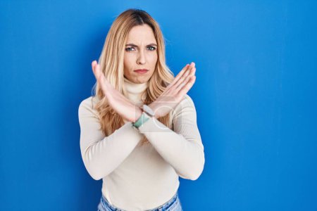 Téléchargez les photos : Jeune femme caucasienne debout sur fond bleu expression de rejet croisant les bras faisant signe négatif, visage en colère - en image libre de droit