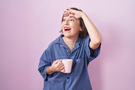 Photo for Middle age hispanic woman drinking a cup coffee very happy and smiling looking far away with hand over head. searching concept. - Royalty Free Image