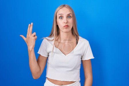 Photo for Young caucasian woman standing over blue background shooting and killing oneself pointing hand and fingers to head like gun, suicide gesture. - Royalty Free Image