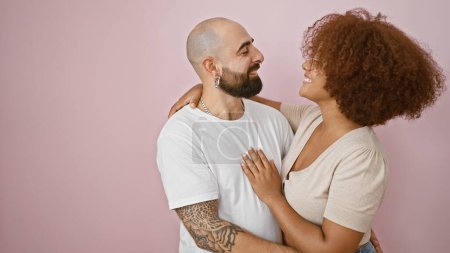 Photo for Joyful beautiful couple exuding confidence, enjoying a casual lifestyle, sharing a warm hug and smiling over isolated pink background while laughing and standing together in love - Royalty Free Image
