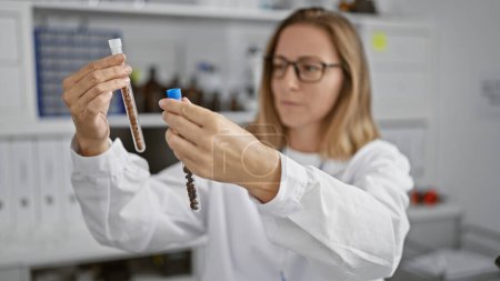 Photo for Attractive, young blonde scientist, seriously concentrating on measuring liquid in test tubes at medical research lab - Royalty Free Image