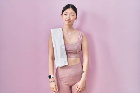 Photo for Chinese young woman wearing sportswear and towel smiling looking to the side and staring away thinking. - Royalty Free Image