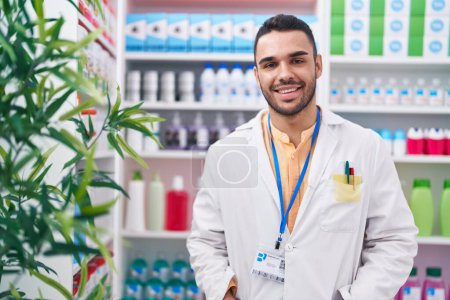 Photo for Young hispanic man pharmacist smiling confident standing at pharmacy - Royalty Free Image