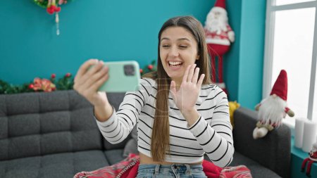 Photo for Young beautiful hispanic woman doing video call waving celebrating christmas at home - Royalty Free Image