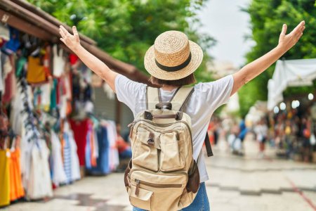 Téléchargez les photos : Femme d'âge moyen touriste portant un sac à dos marchant au marché de rue - en image libre de droit