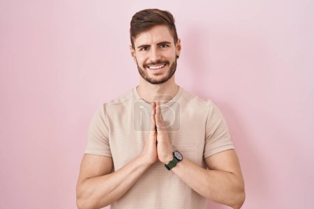Photo for Hispanic man with beard standing over pink background praying with hands together asking for forgiveness smiling confident. - Royalty Free Image