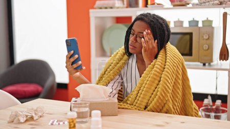 Téléchargez les photos : Femme afro-américaine ayant consultation médicale en ligne assis sur la table étant malade à la salle à manger - en image libre de droit