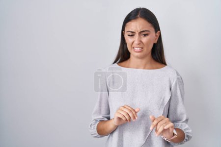 Photo for Young hispanic woman standing over white background disgusted expression, displeased and fearful doing disgust face because aversion reaction. - Royalty Free Image