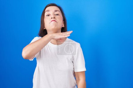 Photo for Middle age hispanic woman standing over blue background cutting throat with hand as knife, threaten aggression with furious violence - Royalty Free Image