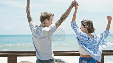 Téléchargez les photos : Beau couple debout avec les mains levées au bord de la mer - en image libre de droit