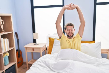 Photo for Young man waking up stretching arms at bedroom - Royalty Free Image