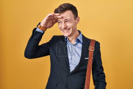 Téléchargez les photos : Homme d'affaires caucasien sur fond jaune très heureux et souriant regardant loin avec la main sur la tête. concept de recherche. - en image libre de droit