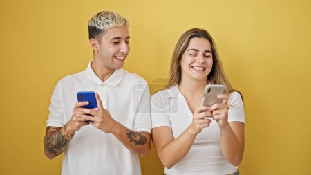 Photo for Beautiful couple using smartphones smiling over isolated yellow background - Royalty Free Image