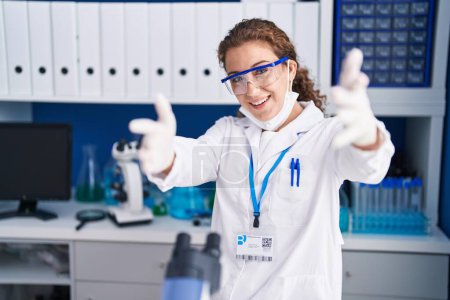 Téléchargez les photos : Jeune femme caucasienne travaillant au laboratoire scientifique regardant la caméra sourire à bras ouverts pour se faire câliner. expression joyeuse embrassant le bonheur. - en image libre de droit