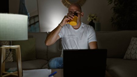 Téléchargez les photos : Jeune homme hispanique utilisant un ordinateur portable boire du café à la maison - en image libre de droit