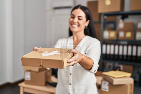 Photo for Young beautiful hispanic woman ecommerce business worker holding package at office - Royalty Free Image