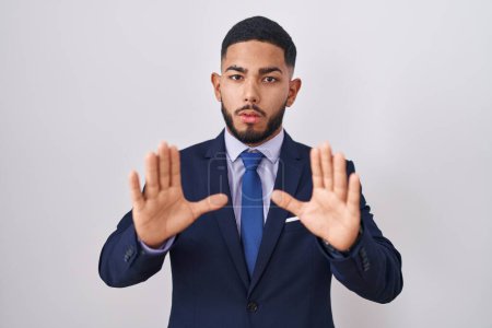 Photo for Young hispanic man wearing business suit and tie moving away hands palms showing refusal and denial with afraid and disgusting expression. stop and forbidden. - Royalty Free Image