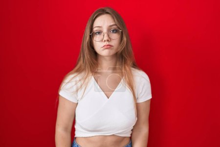 Photo for Young caucasian woman standing over red background depressed and worry for distress, crying angry and afraid. sad expression. - Royalty Free Image