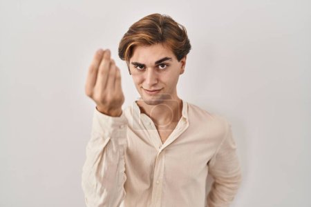 Foto de Young man standing over isolated background doing italian gesture with hand and fingers confident expression - Imagen libre de derechos