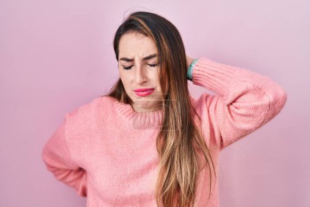 Photo for Young hispanic woman standing over pink background suffering of neck ache injury, touching neck with hand, muscular pain - Royalty Free Image