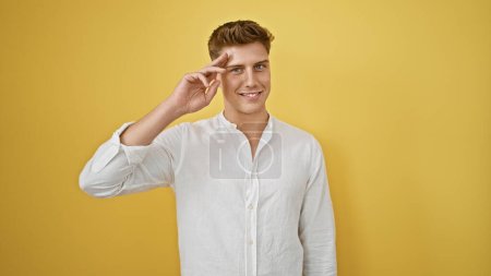Photo for Joyful and confident caucasian man saluting with his fingers, smiling brightly against an isolated yellow background - Royalty Free Image