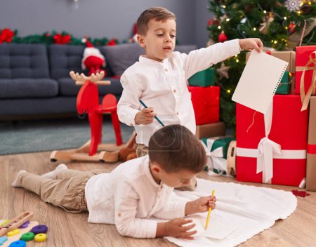 Photo for Adorable boys drawing on paper celebrating christmas at home - Royalty Free Image