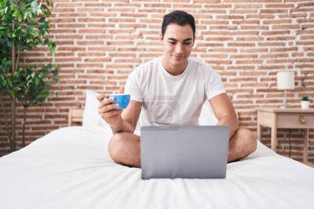 Foto de Joven hispano usando laptop bebiendo café en el dormitorio - Imagen libre de derechos