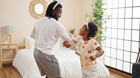 Foto de Afro-americanos padre e hija usando divertido diadema bailando en el dormitorio - Imagen libre de derechos