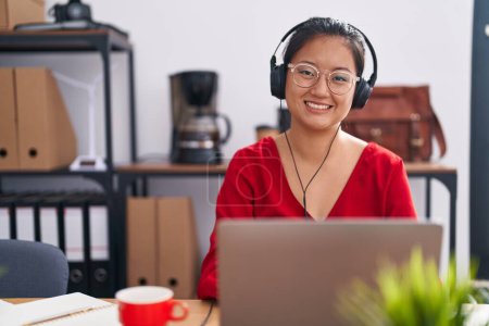 Téléchargez les photos : Jeune femme chinoise agent du centre d'appels souriant confiant travailler au bureau - en image libre de droit