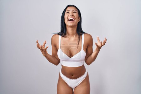 Photo for Hispanic woman wearing lingerie crazy and mad shouting and yelling with aggressive expression and arms raised. frustration concept. - Royalty Free Image