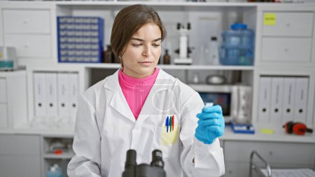 Photo for Young beautiful hispanic woman scientist looking at sample at laboratory - Royalty Free Image