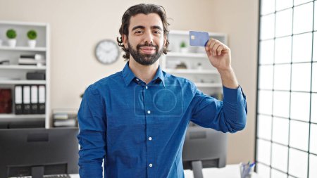 Foto de Joven trabajador de negocios hispano con tarjeta de crédito sonriendo en la oficina - Imagen libre de derechos